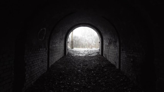 Exit from the old abandoned brick arch tunnel of the 19th century fortification in the woods. Dolling view.