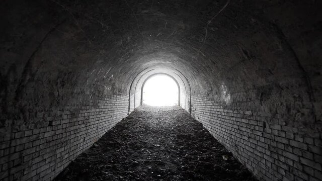 Exit from the old abandoned brick arch tunnel of the 19th century fortification with light in the end. Dolling view.