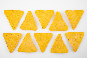 rows of Nachos on a white table. Mexican snack, corn tortilla chips.