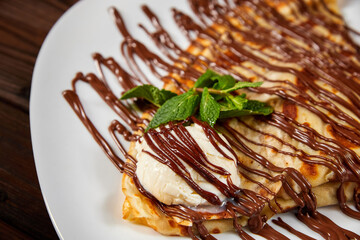 Pancake with a scoop of ice cream and chocolate. Close-up, selective focus