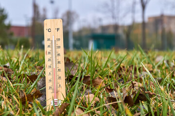 Close-up photo of household alcohol thermometer in grass showing temperature in degrees Celsius....