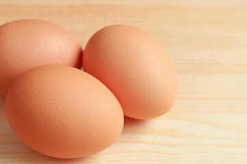 Closeup of Three Chicken Eggs Isolated on Wooden Table with Copy Space