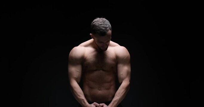 Shirtless muscular man flexing muscles over black background