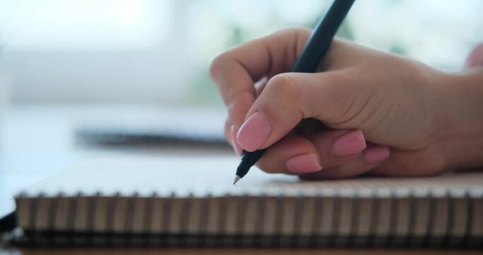 Woman writing in notepad at home