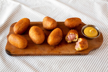 Homemade Mini Corn Dogs on a rustic wooden board, low angle view.