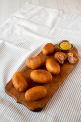 Homemade Mini Corn Dogs on a rustic wooden board, low angle view. Copy space.
