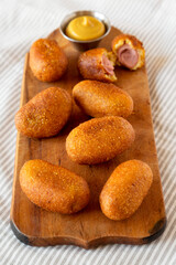 Homemade Mini Corn Dogs on a rustic wooden board, side view.