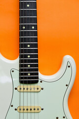 Fototapeta na wymiar Detail of White Electric Guitar on a orange background.
