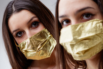 young women wearing golden mask looking at you