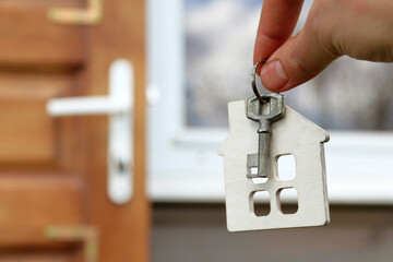 house symbol with a key in hand on the background of the entrance door and window of the building. one-storey individual property