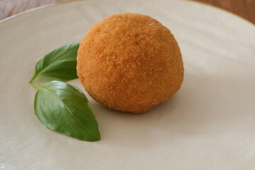 fried arancino with basil, typical Italian food, Italy