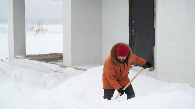 Aftermath of a blizzard. Man shovels snow in the yard in winter