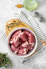 Turkey hearts. Raw turkey hearts in a metal bowl on a light gray table. Top view