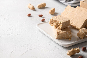 Fototapeta na wymiar Tasty sweet dessert halva prepared from peanut on a white background. Close up. Copy space.