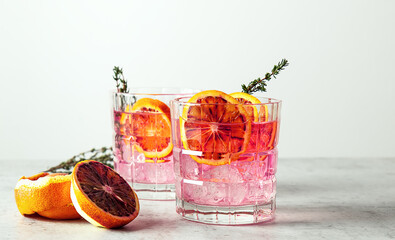 Pink gin cocktail with red blood orange and ice. An alcoholic, refreshing drink.