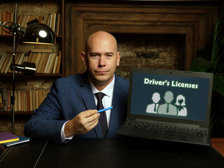Man's hand showing laptop with phrase Driver's Licenses - closeup shot on grey background