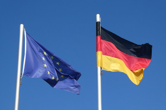 wehende Europafahne und Deutschlandfahne vor blauem Himmel