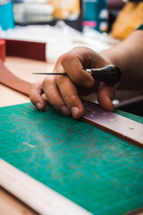 The leather master's hands measure the leather stencil of the belt