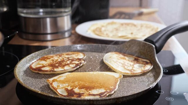 Close-up of mini pancakes on a hot frying pan.