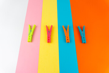 Top view of four different colored plastic clothespins on a background with four different colors