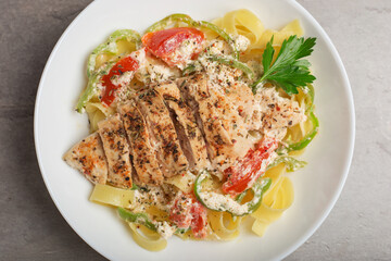 Cajun chicken pasta in a creamy sauce on white plate on stone table. Top view. American cuisine.