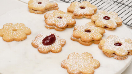 Flower shaped shortbread cookies filled with raspberry jam step by step recipe. Spreading a layer of raspberry jam on baked cookies