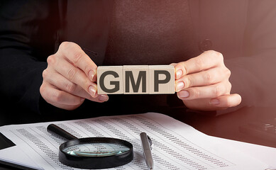 businesswoman holding wooden block with text GMP abbreviation of Good Manufacturing Practice ,...
