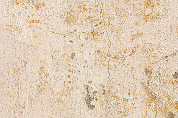 Grunge background of cracked peeling walls with peeled putty in beige tones.