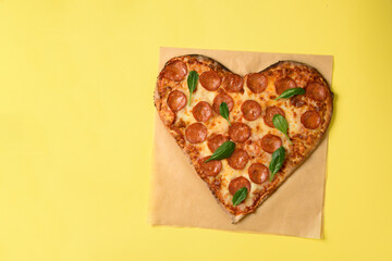 Heart shaped pizza pepperoni on yellow background