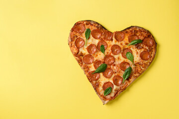 Heart shaped pizza pepperoni on yellow background