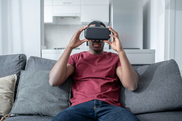 A dark-skinned young man sitting in VR glasses