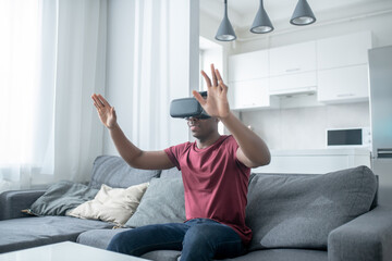 A dark-skinned young man sitting in VR glasses