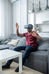 A dark-skinned young man sitting in VR glasses