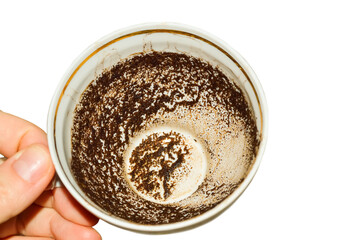 close-up - a cup with patterns of coffee grounds in a female hand on a white background