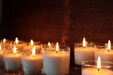 the burning luxury aromatic scented candle glass on the wooden table with background of vintage wooden wall of the cottage in the living room to creat relax ambient during christmas party celebration