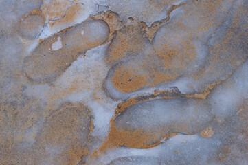 close-up - human footprints turned into ice, sprinkled with sand