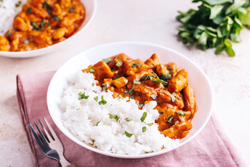Chicken tikka masala and rice in white bowl on neutral table top