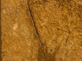 Gold texture rough leaf foil with crack in the middle background. Shiny yellow abstract textured golden stone