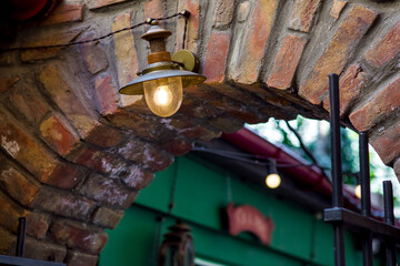 retro street lantern glow with warm light on the brick arch of the old building vault, architecture of european town streets with iron gate, nobody.