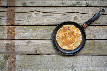 Stack of pancakes on a cast-iron frying pan on a wooden table . Top view. Flat lay.