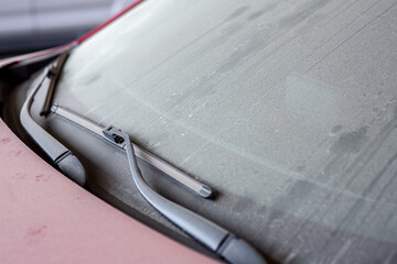 windshield wipers of a dirty car covered with a layer of dust and dry dirt, a close-up of a part of...