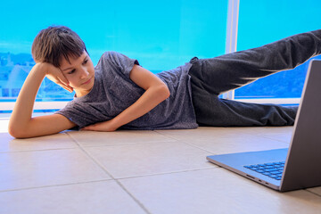 Kid watching online video on laptop computer and doing sport fitness exercises on balcony. Sport, healhty lifestyle, active leisure,stay at home entertainment