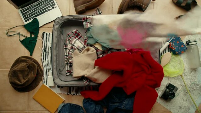 Person packs suitcase in rush, late for flight or trip. Throw clothes in bag, mess and chaos in teenager room. Stressed and anxious last minute packing. Concept always late or missing flight