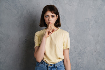 Attractive young serious woman showing silence gesture