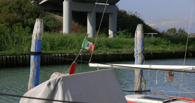 Small italian flag waving on the wind on one of the moored motor boats slow motion