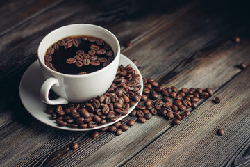 saucer with coffee beans and white cup on a wooden table side view Copy Space