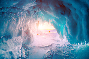 Ice cave on Baikal lake in winter. Blue ice and icicles in the sunset sunlight. Olkhon island,...