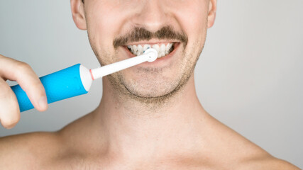 Man with bristles brushing teeth, daily hygiene procedure. Close-up portrait of man with modern...