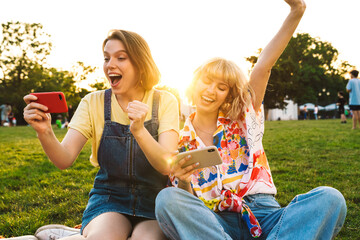 Image of excited women making winner gesture and playing online games