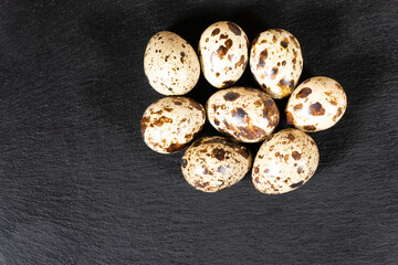 Boiled spotted quail eggs  on black stone plate , isolated on white background. Healthy Food Products Concept.
